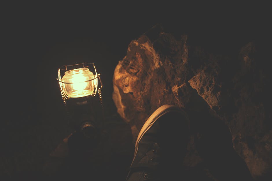 Foot near lantern illuminating rocks at night, evoking warmth and adventure.